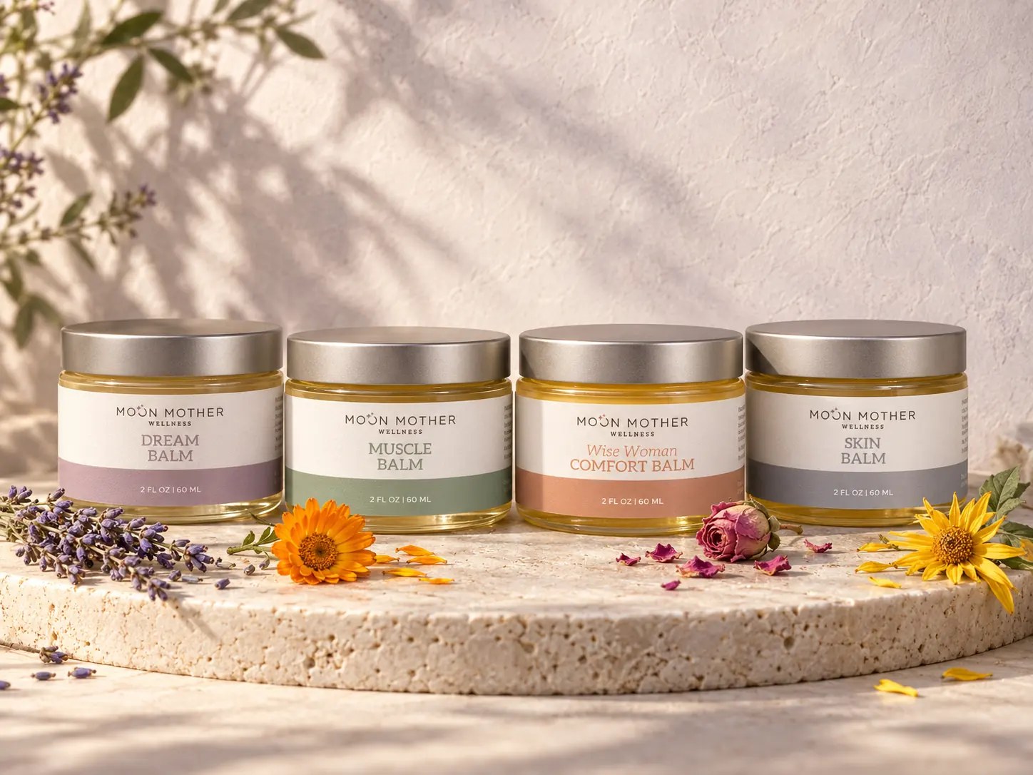 Dream, Muscle, Wise Woman Comfort and Skin balms lined up on a stone slab with lavender, calendula, rose and arnica